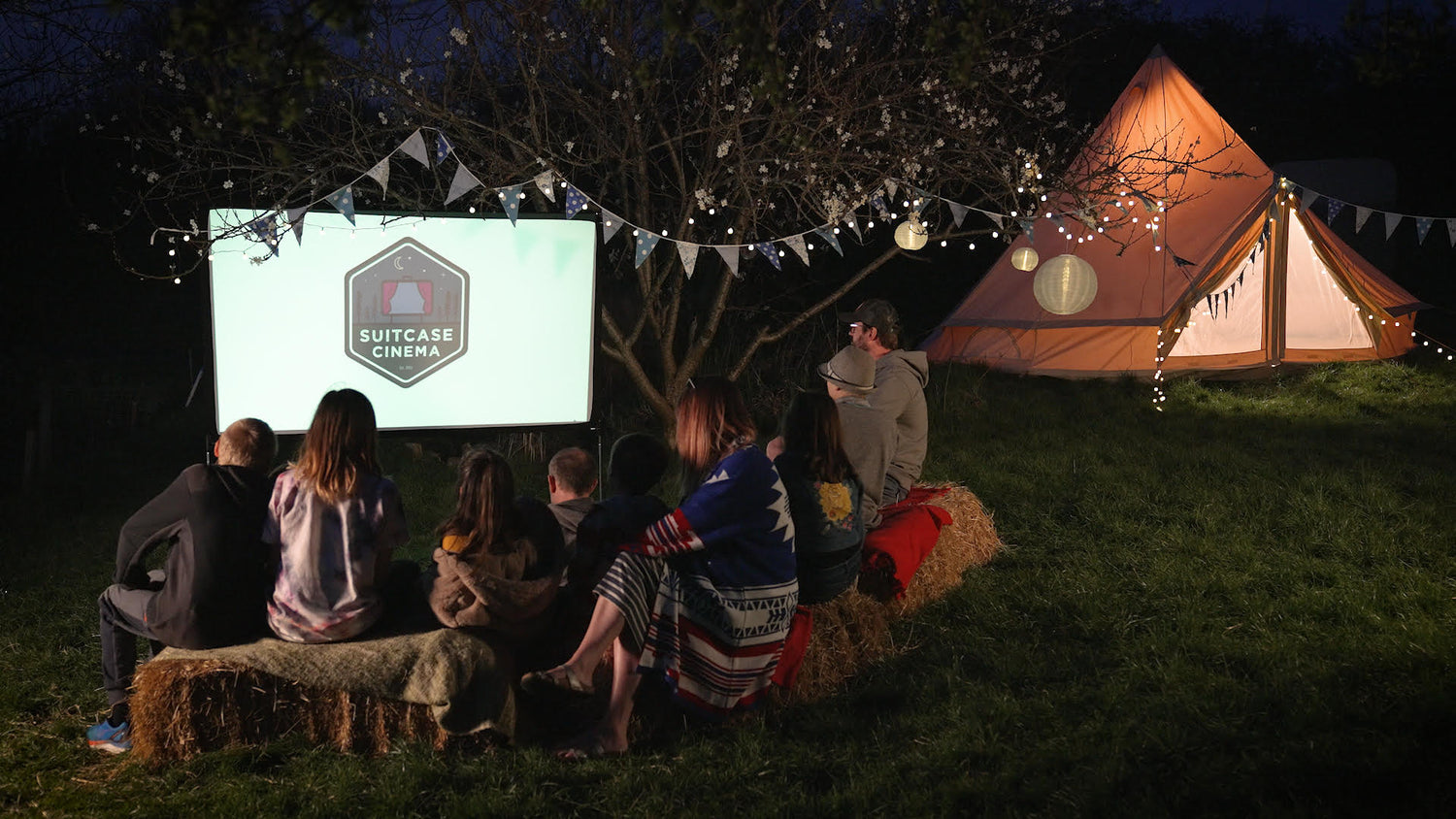 Image of family watching pop up cinema by teepee tent
